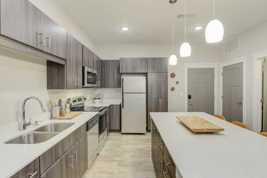 Checking kitchen appliances like refrigerators, ovens, and dishwashers should be part of your move-in and move-out checklists. Apartment kitchen with large island, stainless appliances, and decorative lighting