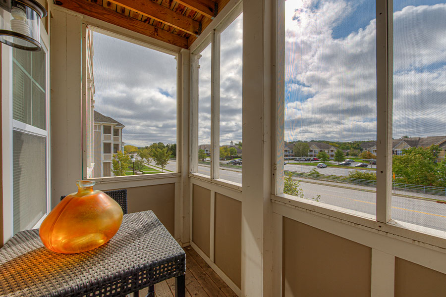 Screened patio with a small table and an orange vase. Located at Ivy Flats Apartments.