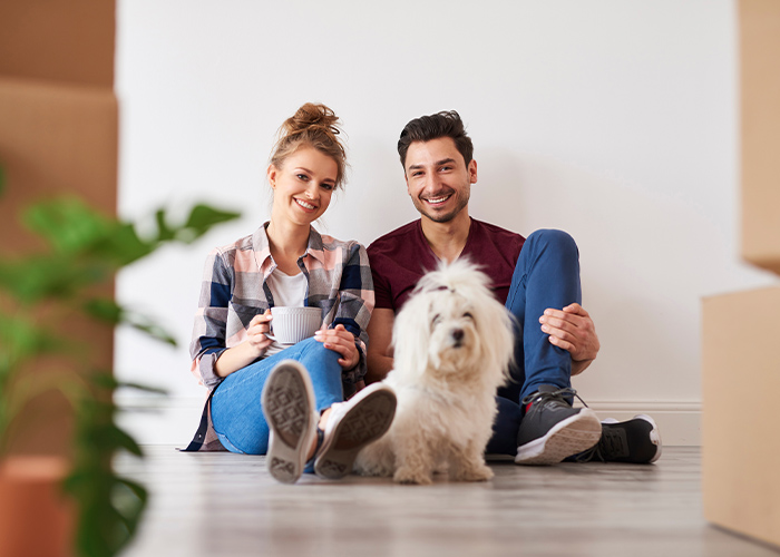 Pet-friendly apartments. Couple sitting on the floor with a dog and boxes.